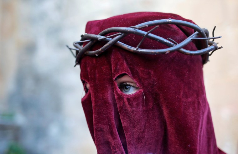 Image: A woman, penitent of Los Gitanos brotherhood, leaves a church as she takes part in a procession during Holy Week in Ronda