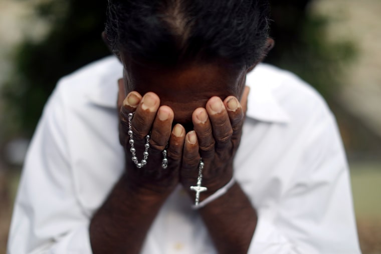 Image: A person mourns at a grave of a victim, two days after a string of suicide bomb attacks on churches and luxury hotels across the island on Easter Sunday, at Sellakanda Catholic cemetery in Negombo