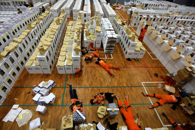 Image: Workers lay during a break as they prepare election materials in a warehouse in Jakarta