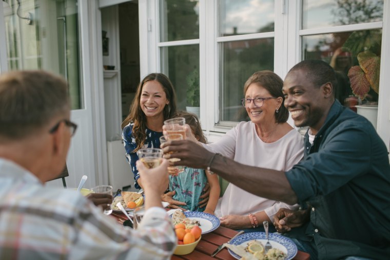 Happy multi-generation family toasting drinks at table during garden party