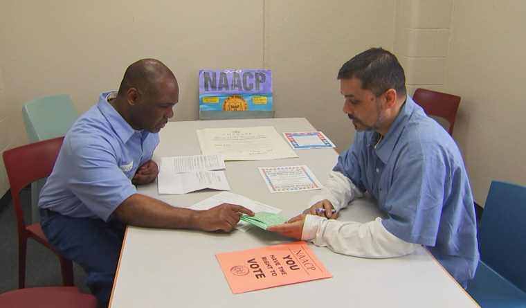 Prisoners Foster Bates, left, and Santanu Basu go over materials they use to register fellow inmates to vote