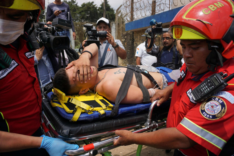 Image: An injured inmate is carried away on a stretcher