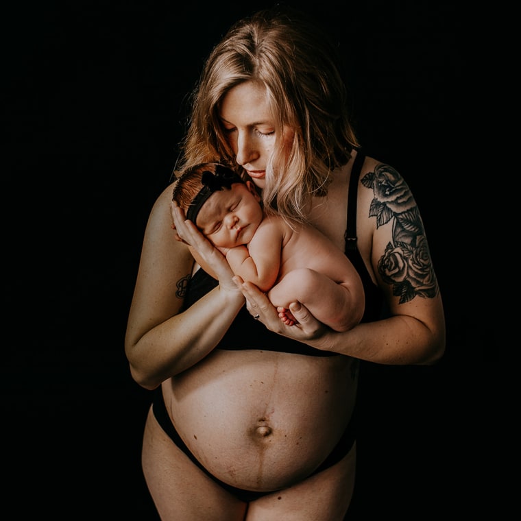 New mom cradles her baby in a professional postpartum photograph.