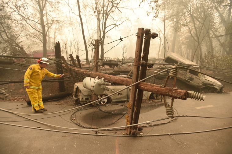 Image: CalFire firefighter Scott Wit surveys burnt out vehicles near a fallen power line after the Camp fire tore through Paradise, California, on Nov. 10, 2018.