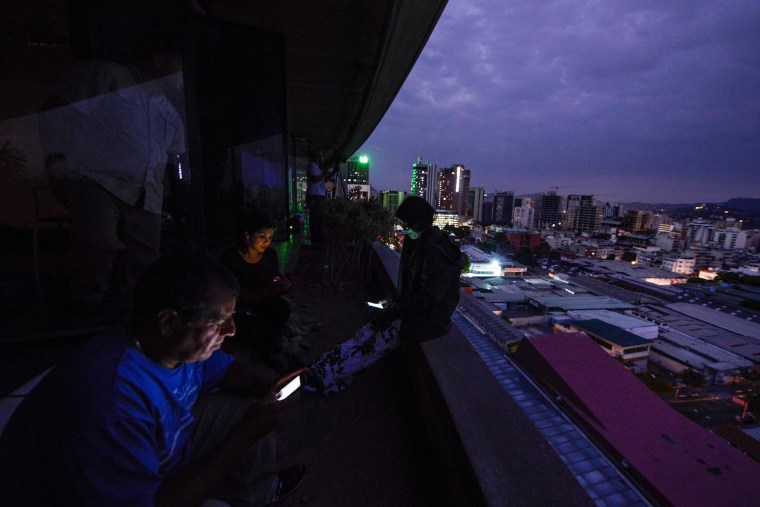 People use their smartphones during a power cut in Caracas