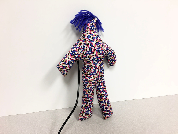 IMage: A doll-like fabric body with blue hair provokes users with an irritating laugh until they hit it into submission.