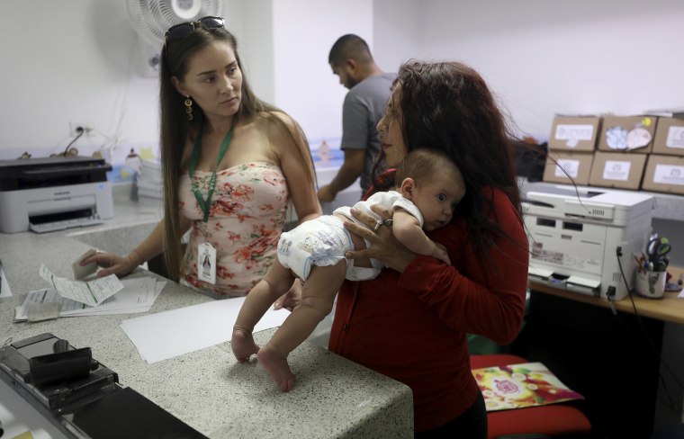 Image: Arelys Pulido, right, holds her two-month-old daughter Zuleidys Antonella Primera as they are processed for her baby's birth certificate at the Erazmo Meoz hospital in Cucuta