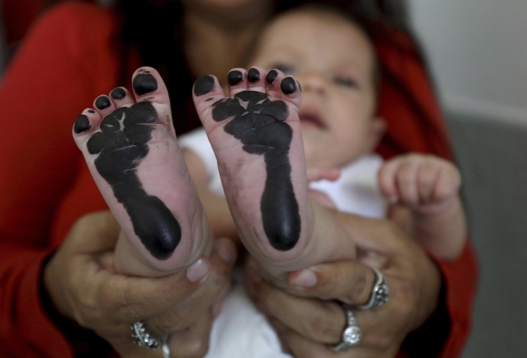 Image: Arelys Pulido holds her two-month-old daughter Zuleidys Antonella Primera after she had her feet prints taken for her birth certificate at the Erazmo Meoz hospital in Cucuta, on Colombia's border with Venezuela