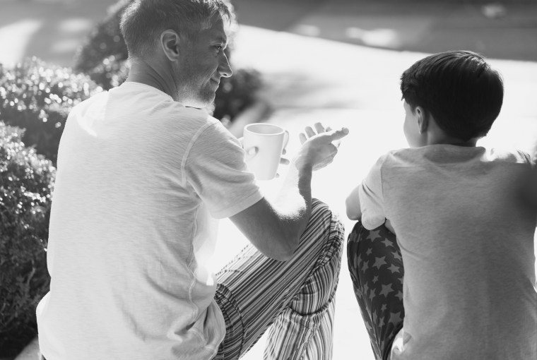 Father with coffee talking to son on front stoop