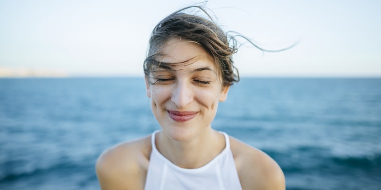 Young woman smiling with eyes closed with sea background