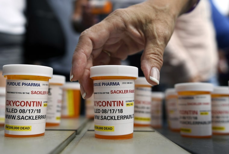 Image: Family and friends who have lost loved ones to OxyContin and opioid overdoses leave pill bottles with protest messages on them outside the headquarters of Purdue Pharma