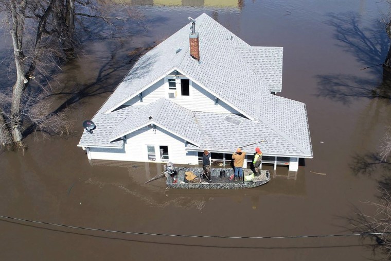 Image: Lanni Bailey and a team from Muddy Paws Second Chance Rescue enter a flooded house to pull out several cats during flooding of the Missouri River near Glenwood