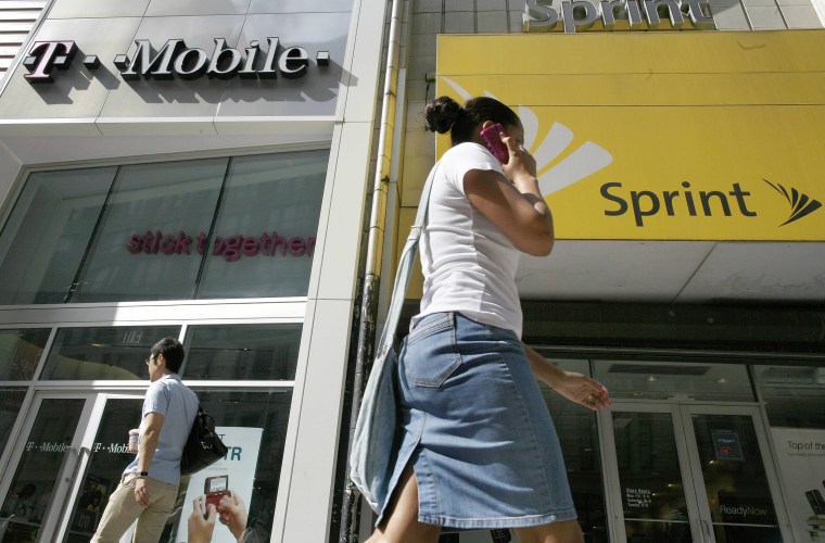 Image: A woman talking on her phone as she walks past T-mobile and Sprint wireless stores in New York