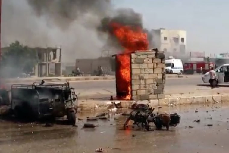 Image: A burnt out car and a motorbike on a road in a town, said to be Saraqib, Idlib province, Syria