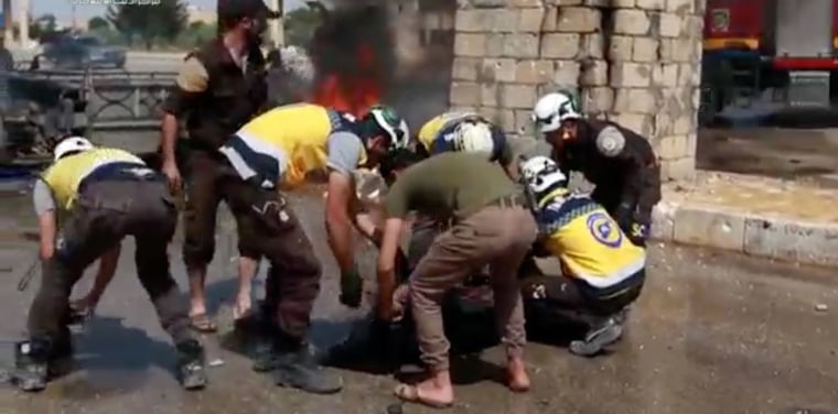 Image: White Helmets members also know as the Syrian Civil Defence putting a body into a bag in a town, said to be Saraqib, Idlib