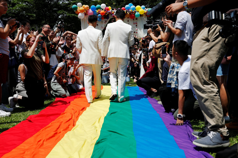 Image: Gay newlyweds walk on a giant rainbow flag at a pro same-sex marriage party after registering their marriage in Taipei