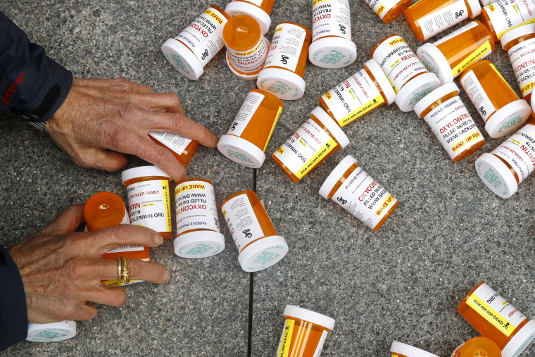 A protester gathers containers depicting OxyContin prescription pill bottles after a demonstration against the FDA's opioid prescription drug approval practices on April 5, 2019, in front of the Department of Health and Human Services' headquarters in Washington.