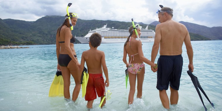 Parents with children (10-12) in water with snorkel gear, rear view