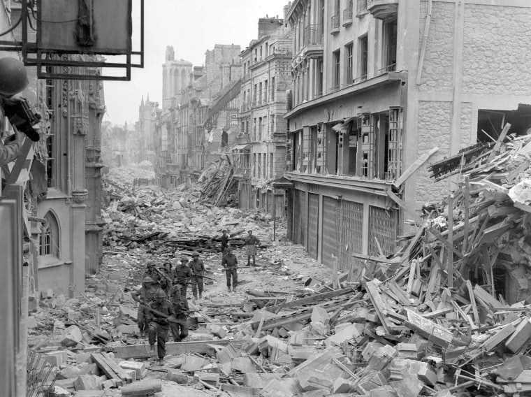 Image: Handout photo of Canadian troops patrolling along the destroyed Rue Saint-Pierre after German forces were dislodged from Caen