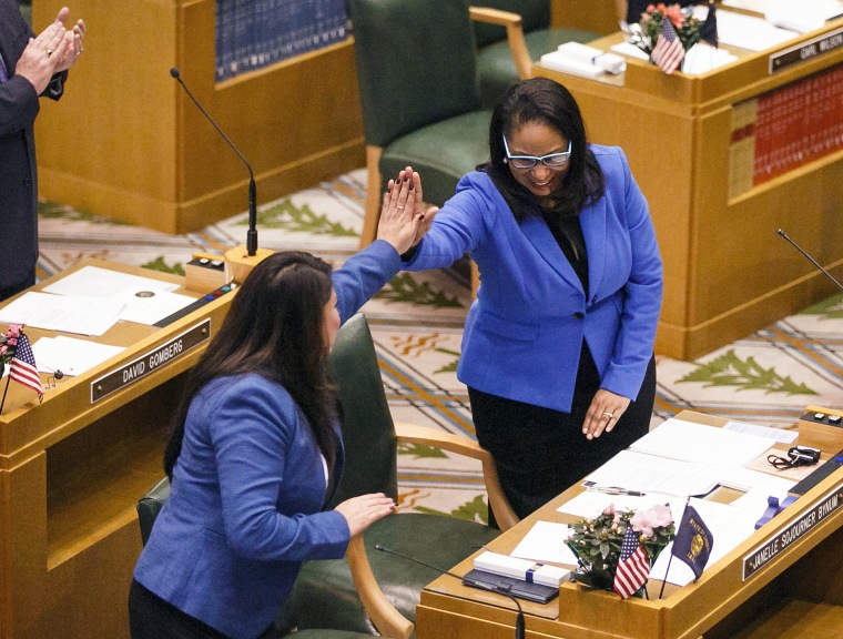 Rep. Teresa Alonso Leon, left, and Rep. Janelle Sojourner Bynum high-five after members of the House of Representatives are sworn into office at the Oregon State Capitol in Salem, Oregon on Jan. 9, 2017