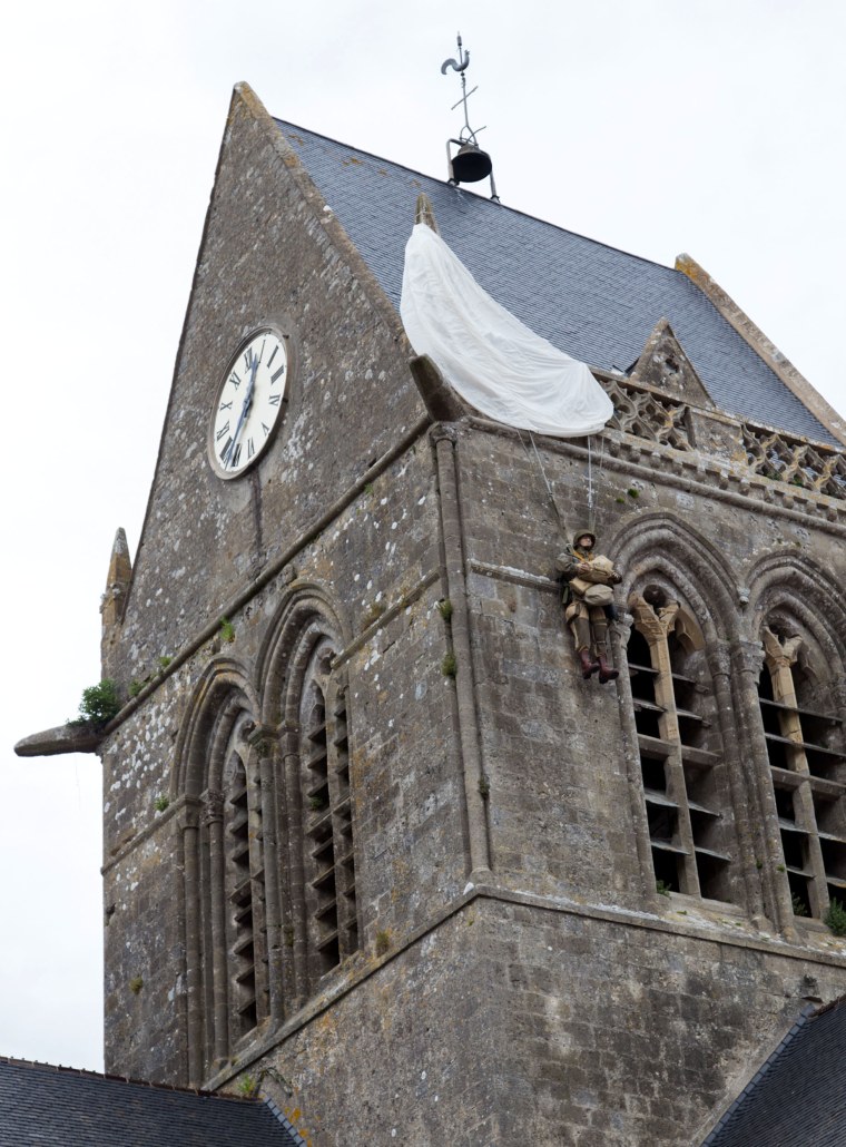 Image: Church in Sainte-mere-eglise, where a fake parachutist hangs on the bell tower in memory of John Steele
