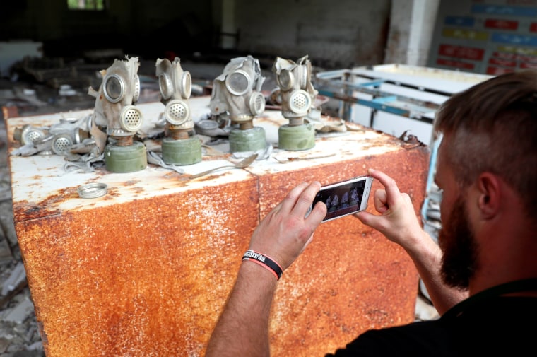 Image: A visitor takes a photo of gas masks at the former Soviety Army base near the Chernobyl nuclear power plant in Ukraine on June 2, 2019.
