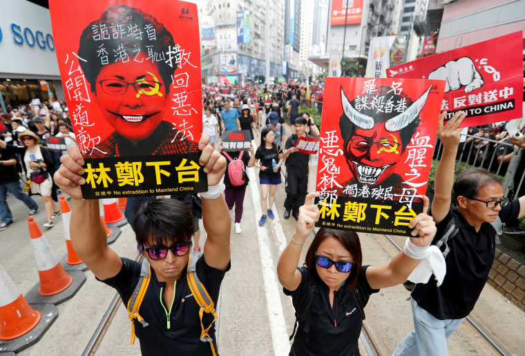 Image: Protesters hold placards with the face of the island's chief executive, Carrie Lam. 