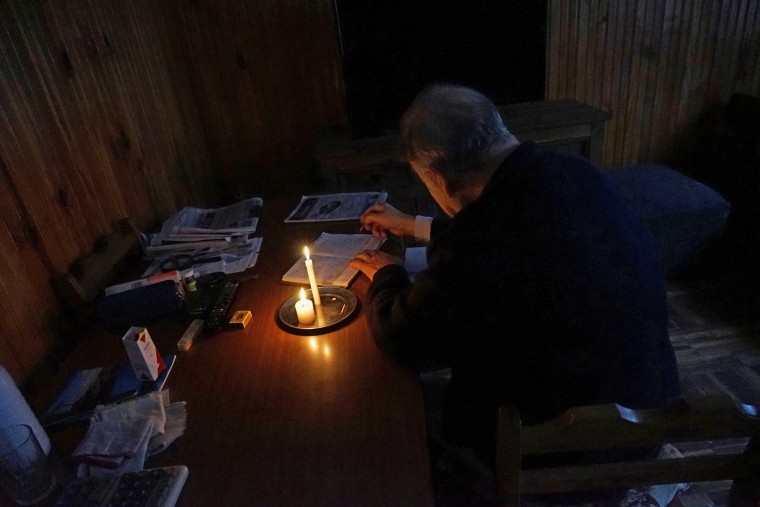 Image: A man writes by candlelight as his neighbourhood Parque Batlle goes without electricity after a massive blackout in Argentina, in Montevideo