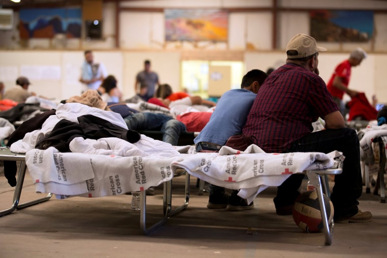 Image: Migrants sit on a cot inside a shelter at the Southwestern New Mexico State Fairgrounds in Deming