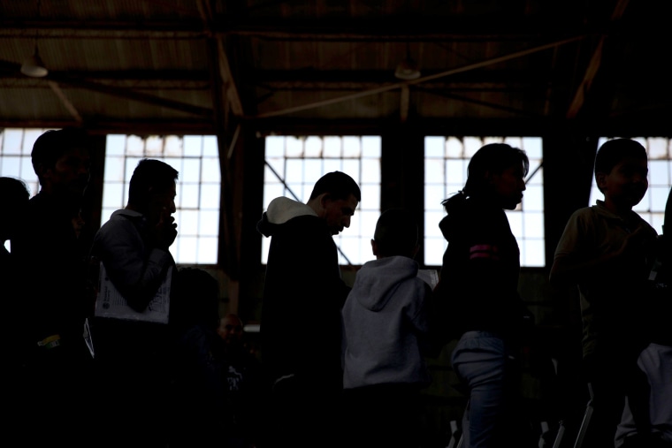Image: Migrants wait to be transported from the intake processing area to the shelter at the Southwestern New Mexico State Fairgrounds in Deming