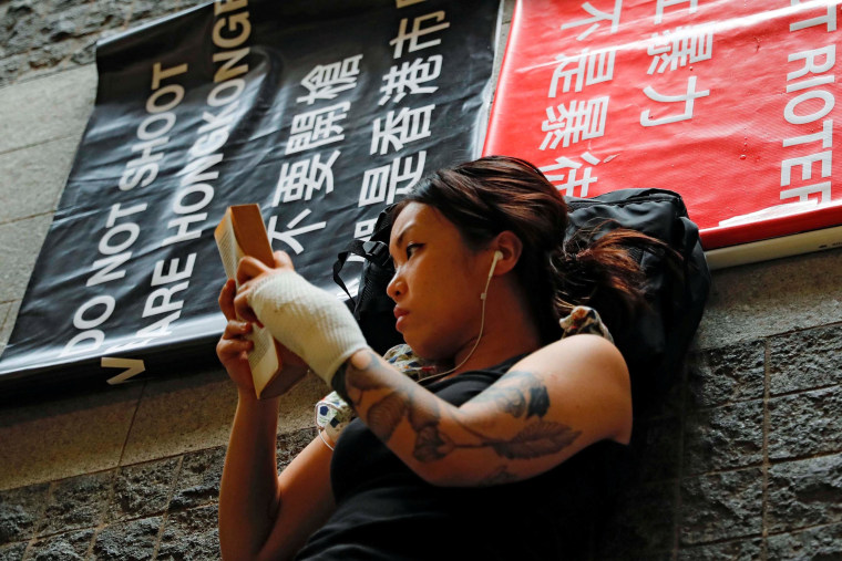 Image: A demonstrator looks into her phone outside the Legislative Council building during a demonstration demanding Hong Kong's leaders to step down and withdraw the extradition bill, in Hong Kong