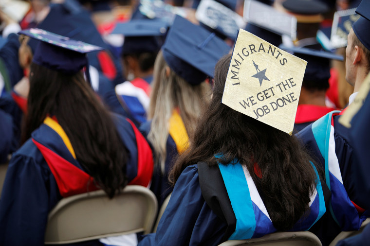 A graduate wears a mortar board adorned with a message in support of immigrants before the start of commencement exercises at Liberty University in Lynchburg, Virginia