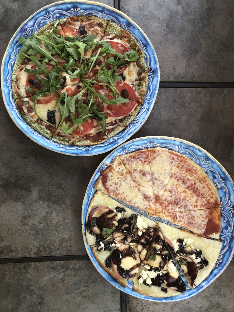 Trader Joe's Broccoli &amp; Kale Pizza Crust (left) with tomato sauce, mozzarella, arugula and olives beside a sweet and simple savory version of Trader Joe's Cauliflower Pizza Crust (right).