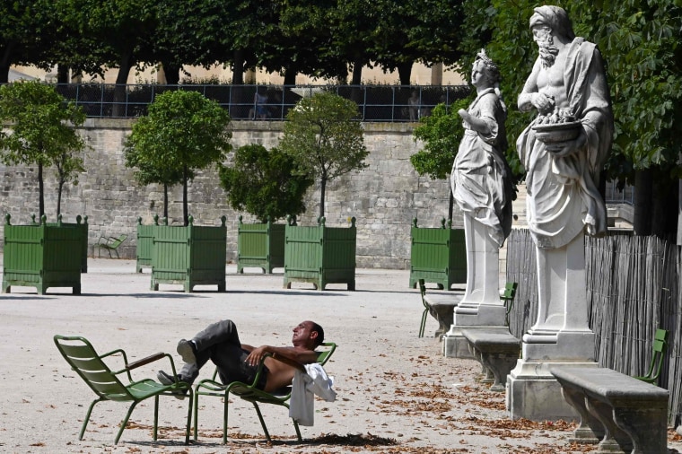 Image: A man sleeps on chairs in the Tuileries Garden in Paris