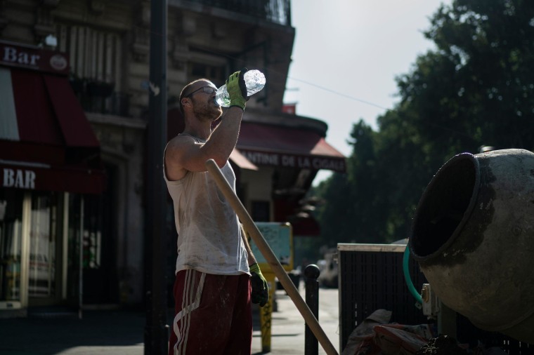 Image: A worker drinks water on a construction site during a heat wave in Paris