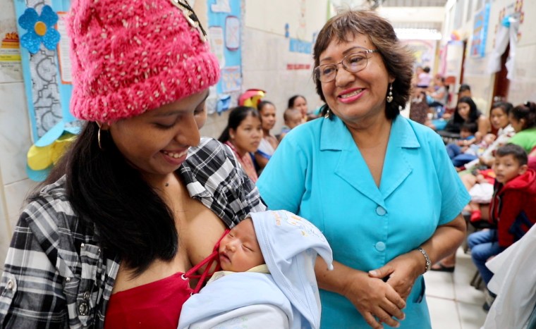 Image:  Nurse Clara with a mother and her baby. The baby gained significant weight after Clara paid them a home visit.