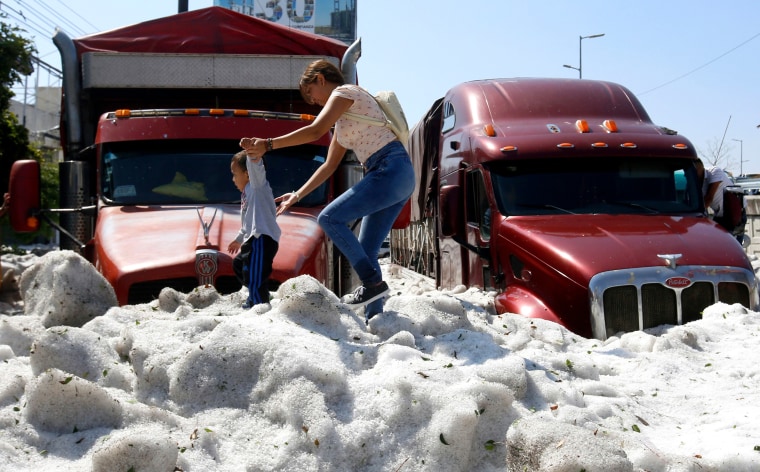 Image: A woman and child walk on a pile of hail in Guadalajara, Mexico, on June 30, 2019.