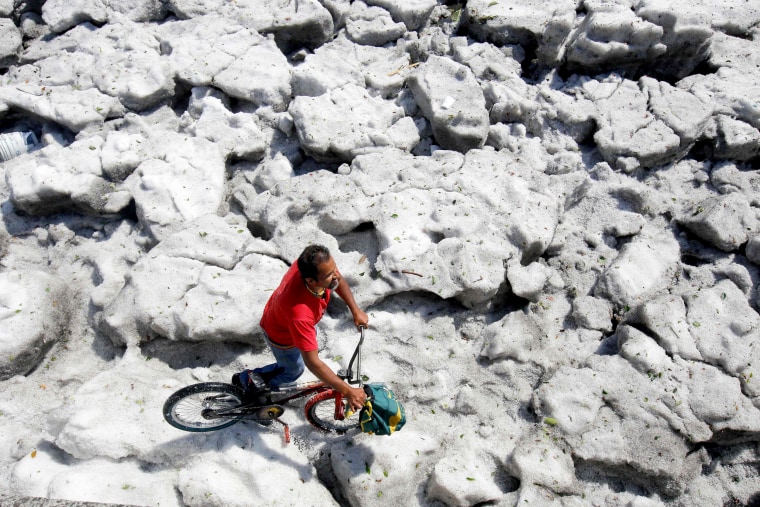 Image: A man with a bike walks on top of the hail in Guadalajara.