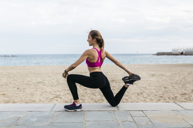 Young woman stretching and warming up for training at the beach