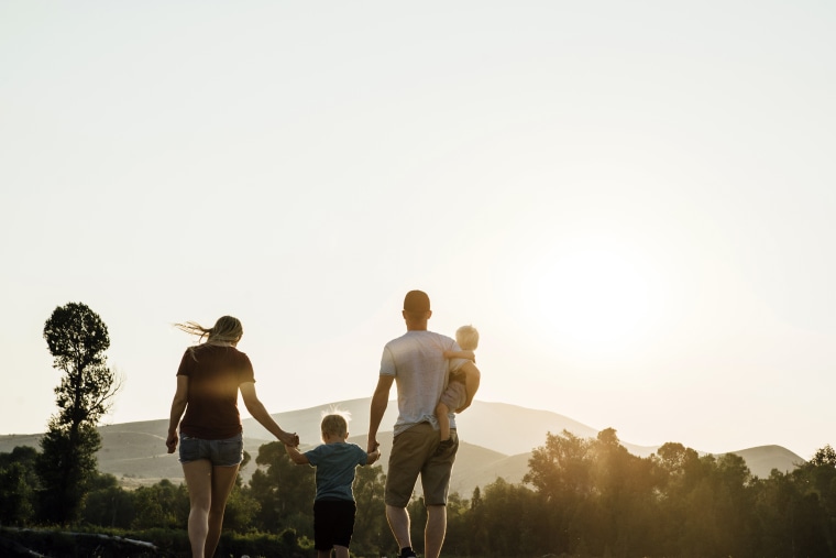 Family walking on field against clear sky during sunset