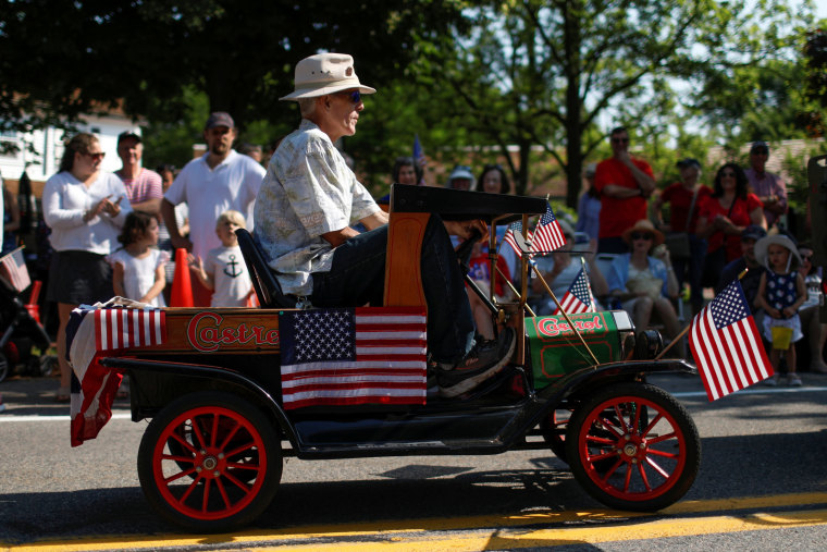 Image: A man rides in a miniature a car during the annual 4th of July parade in Barnstable Village on Cape Cod, Massachusetts