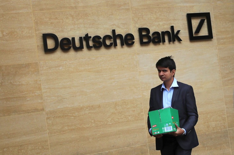 Image: A man carrying a box leaves a Deutsche Bank office in London