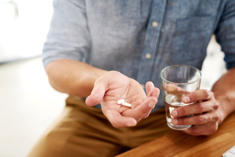 Image: Closeup shot of an unrecognisable man holding a glass of water and medication in his hands