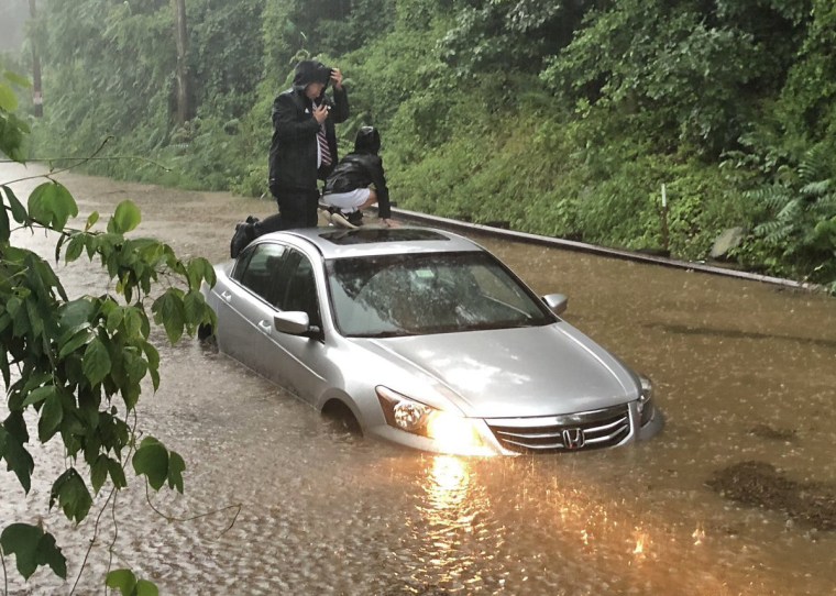 Motorists climb on the roof of their car during flooding in Washington, D.C.