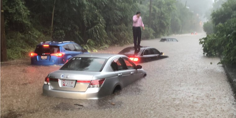 Motorists climb on the roof of their car during flooding in Washington, D.C.