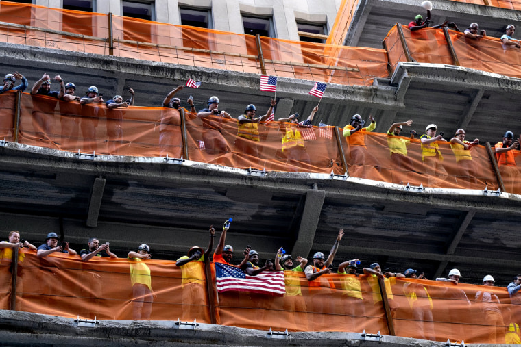 Image: Construction workers wave flags as the U.S. women's soccer team travels up Broadway during the parade in New York on July 10, 2019.