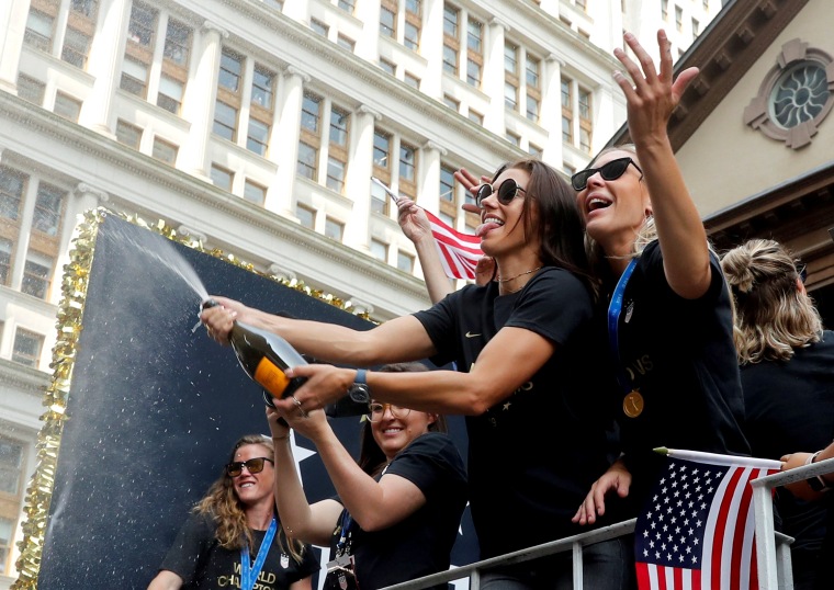 Image: Allie Long and Alex Morgan spray champagne on fans during the ticker-tape parade on July 10, 2019.