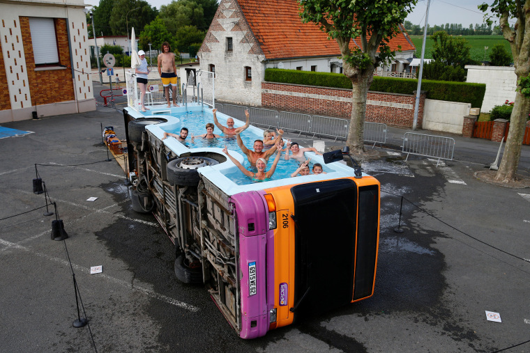 Image: People bathe in a decommissioned city bus named \"le bus piscine\", an artwork by the French artist Benedetto Bufalino in Gosnay near Bethune