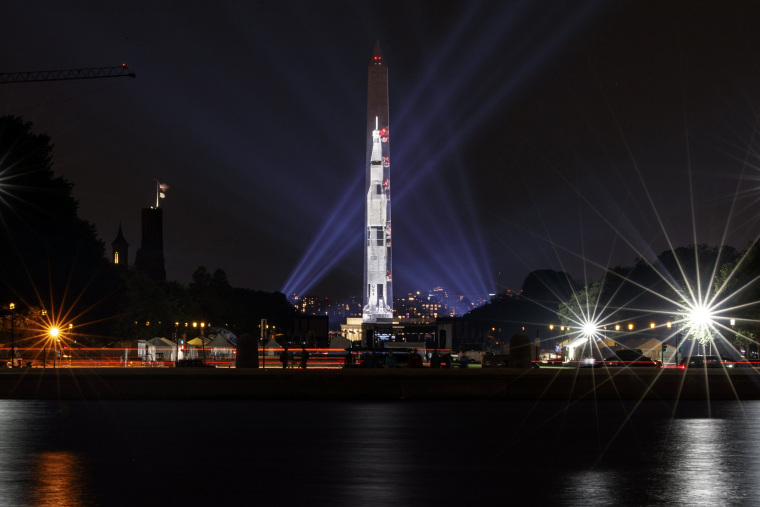 Image: The image of a 363-foot Saturn V rocket is projected on the east face of the Washington Monument