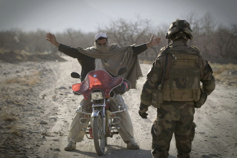 Image: A soldier inspects an Afghan man on motorcyle near Tagab in Kapisa Province
